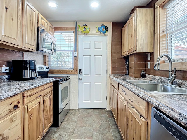 kitchen with light brown cabinetry, stainless steel appliances, tasteful backsplash, and a sink