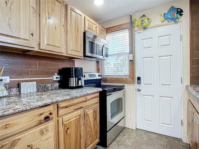 kitchen featuring light brown cabinetry, stainless steel appliances, and light stone counters