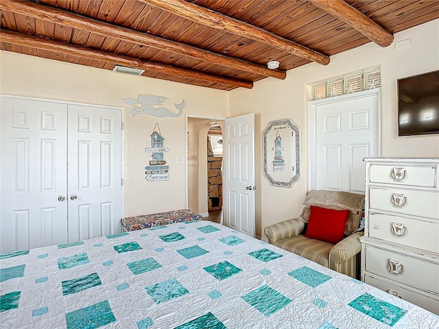 unfurnished bedroom featuring beamed ceiling, arched walkways, wood ceiling, and a closet