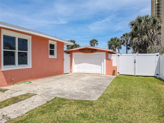 exterior space with an outbuilding, a gate, fence, concrete driveway, and a garage