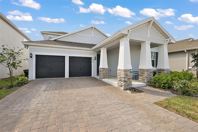 view of front of home with stone siding, stucco siding, decorative driveway, and a garage