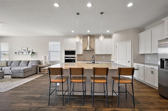 kitchen featuring white cabinetry, wall chimney exhaust hood, dark wood-style floors, and appliances with stainless steel finishes