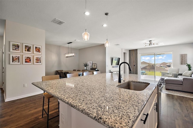 kitchen featuring dark wood-type flooring, open floor plan, visible vents, and a sink