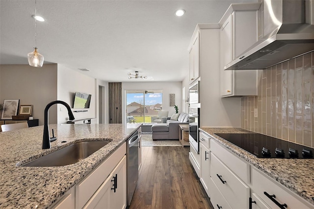 kitchen with dark wood-style floors, a sink, appliances with stainless steel finishes, wall chimney range hood, and open floor plan