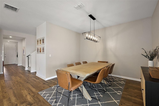 dining space with dark wood-style floors, visible vents, a chandelier, and baseboards