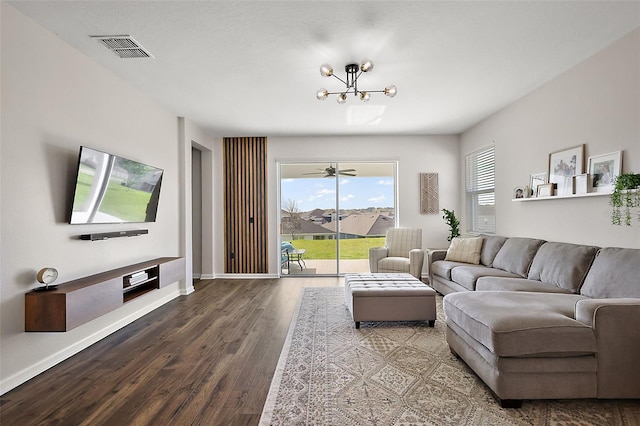 living area featuring wood finished floors, visible vents, a chandelier, and baseboards