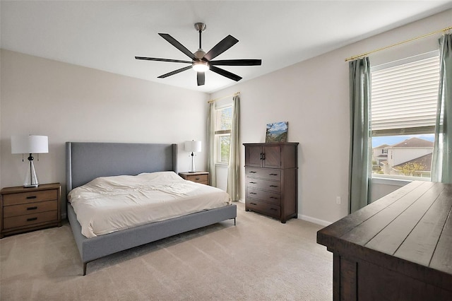 bedroom featuring light colored carpet, baseboards, and a ceiling fan