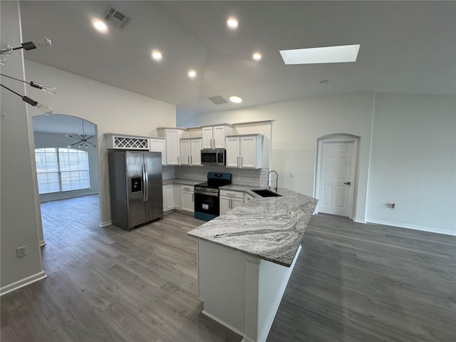 kitchen with visible vents, a peninsula, arched walkways, stainless steel appliances, and a sink