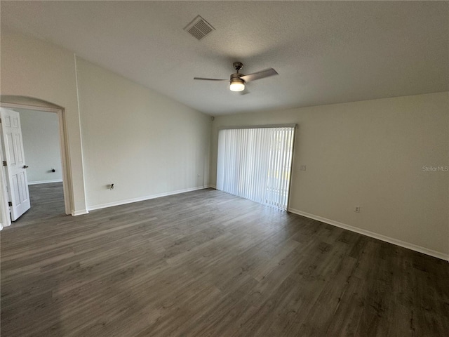 spare room with a ceiling fan, visible vents, arched walkways, dark wood-type flooring, and a textured ceiling