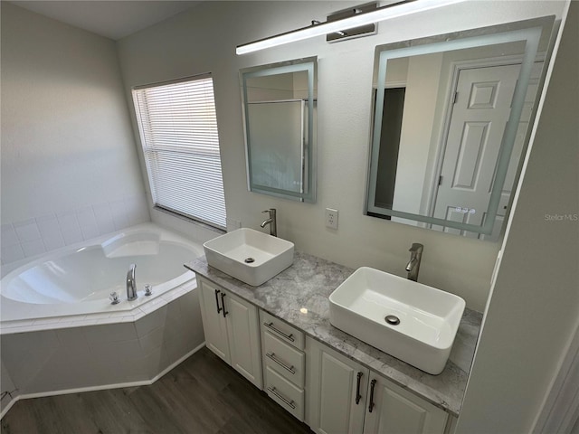 bathroom with a sink, wood finished floors, a bath, and double vanity