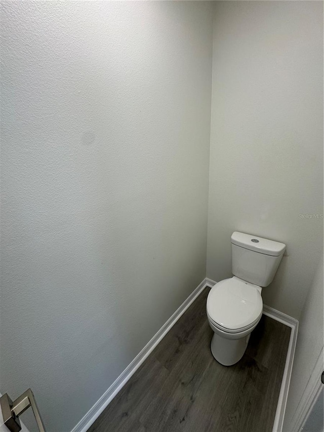 bathroom with toilet, wood finished floors, and baseboards