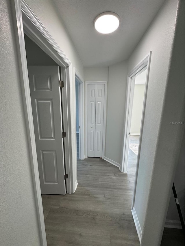 hallway with baseboards and wood finished floors