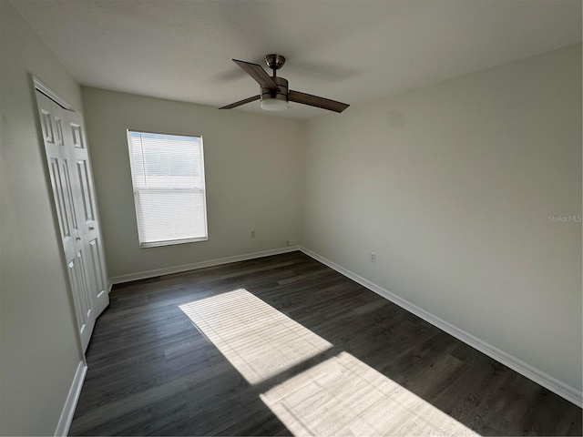 unfurnished bedroom featuring a closet, baseboards, dark wood-type flooring, and a ceiling fan