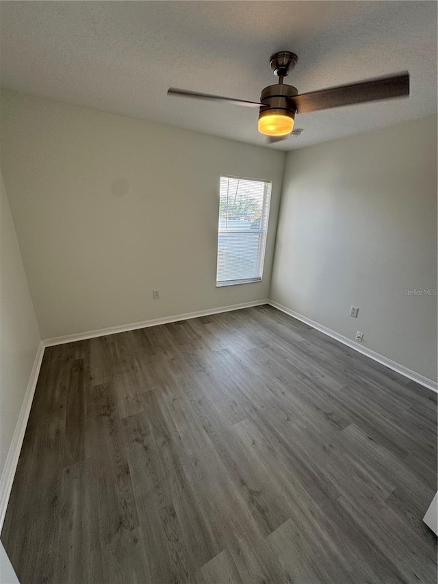 unfurnished room with ceiling fan, a textured ceiling, dark wood-type flooring, and baseboards