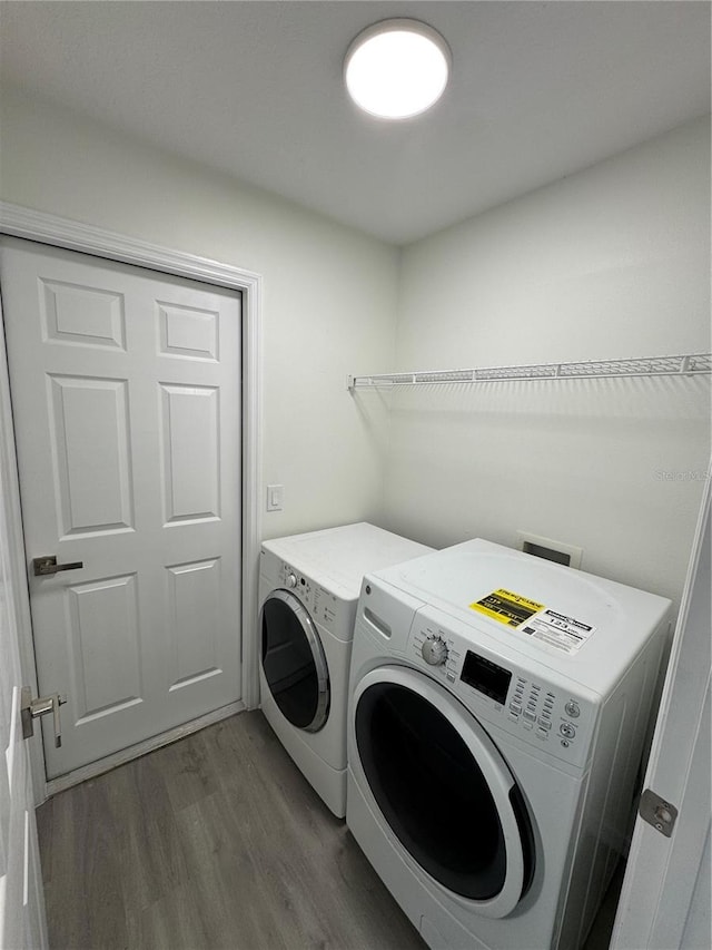 laundry area featuring laundry area, wood finished floors, and washer and clothes dryer