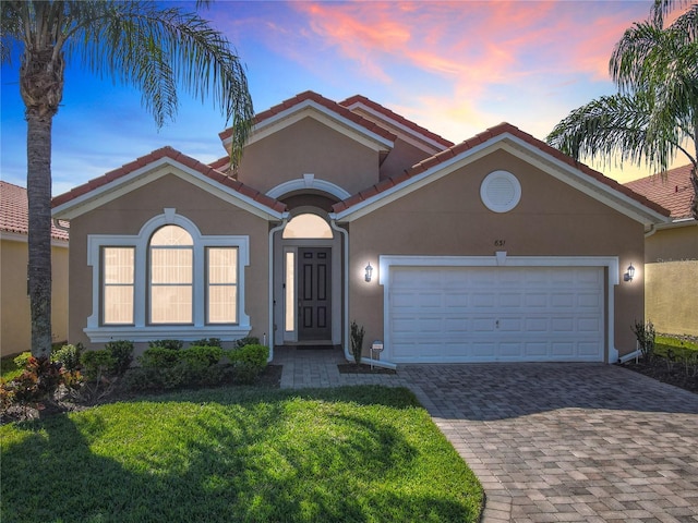 mediterranean / spanish-style house with decorative driveway, a garage, and stucco siding