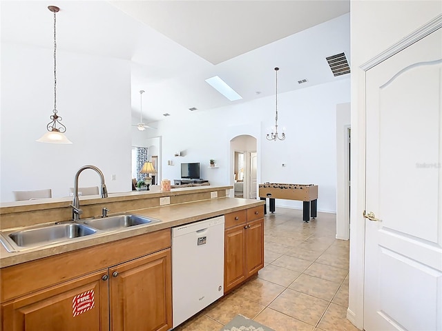 kitchen with dishwasher, light tile patterned floors, hanging light fixtures, arched walkways, and a sink