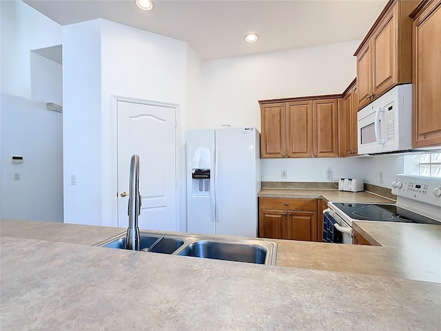 kitchen featuring white appliances, recessed lighting, a sink, light countertops, and brown cabinets