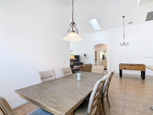 dining space featuring light tile patterned floors, visible vents, arched walkways, and baseboards