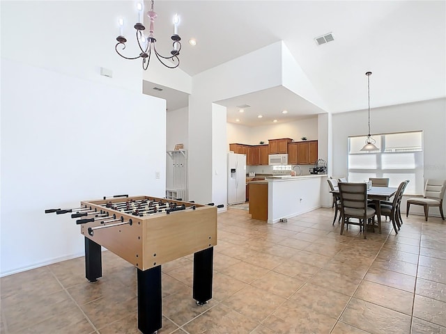 rec room with visible vents, light tile patterned floors, a notable chandelier, high vaulted ceiling, and a sink