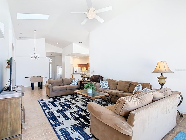 living area with a skylight, high vaulted ceiling, light tile patterned flooring, and ceiling fan with notable chandelier