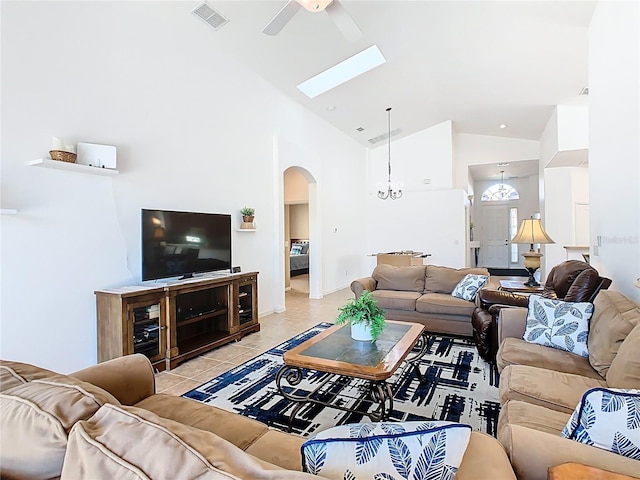 living area featuring light tile patterned floors, visible vents, high vaulted ceiling, arched walkways, and ceiling fan with notable chandelier