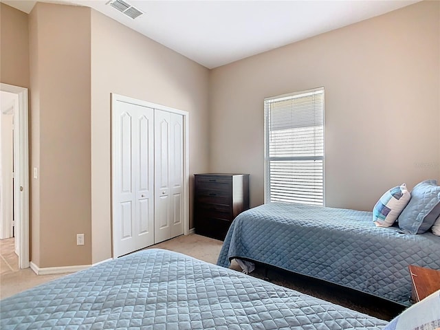 bedroom featuring light colored carpet, visible vents, a closet, and baseboards