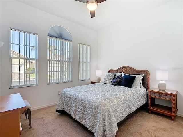 bedroom featuring baseboards, light colored carpet, and ceiling fan