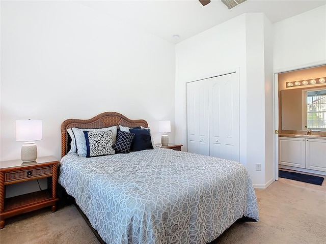 bedroom with a closet, light colored carpet, ensuite bath, and a sink