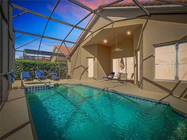 view of swimming pool featuring glass enclosure, a pool with connected hot tub, a ceiling fan, and a patio area