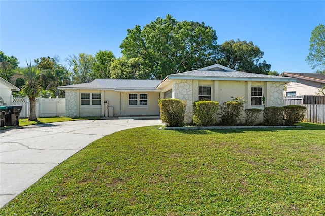 ranch-style house with stone siding, a front lawn, driveway, and fence