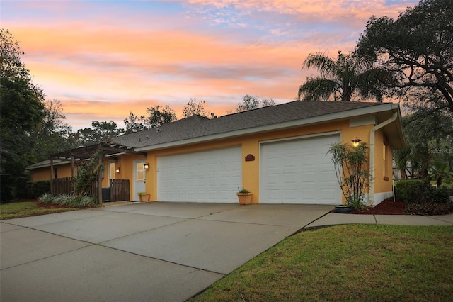 ranch-style home featuring concrete driveway, an attached garage, fence, and stucco siding