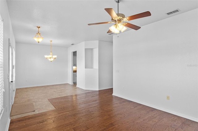 unfurnished room featuring visible vents, baseboards, wood finished floors, and ceiling fan with notable chandelier