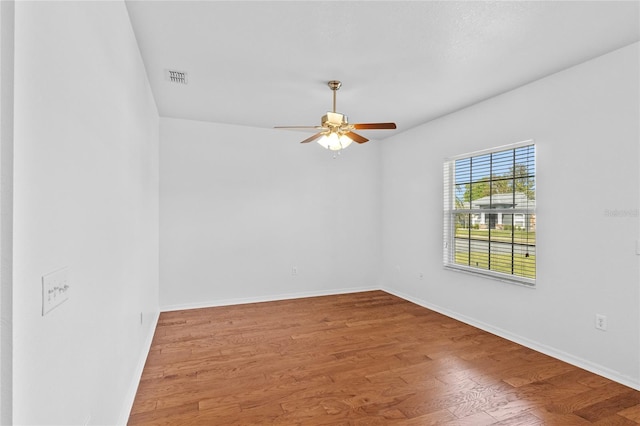 unfurnished room featuring visible vents, baseboards, wood finished floors, and a ceiling fan