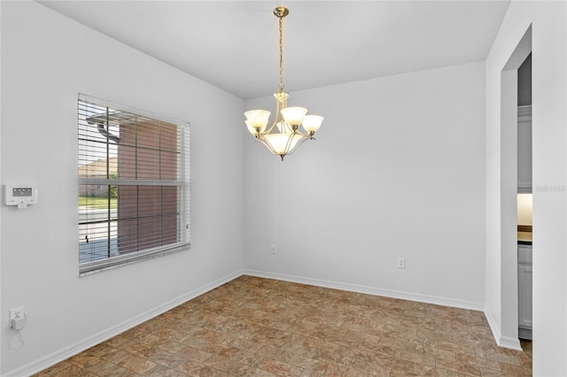 empty room with baseboards and a chandelier