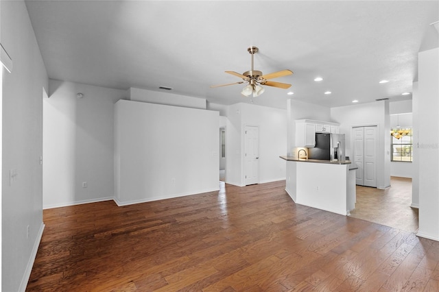 unfurnished living room featuring visible vents, baseboards, recessed lighting, ceiling fan with notable chandelier, and wood-type flooring