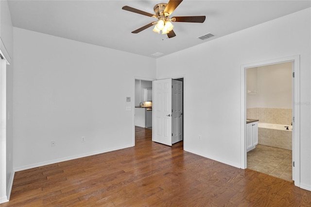 unfurnished bedroom with visible vents, ensuite bath, baseboards, and wood finished floors