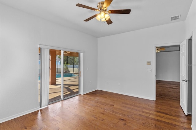 spare room featuring ceiling fan, visible vents, baseboards, and wood finished floors