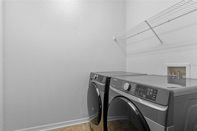 clothes washing area featuring laundry area, stone finish floor, baseboards, and separate washer and dryer