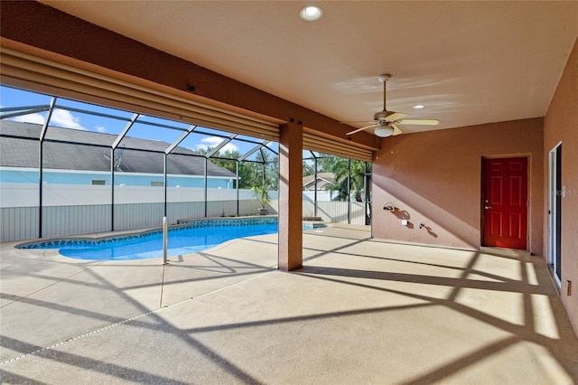 view of pool featuring glass enclosure, a patio, fence, a fenced in pool, and ceiling fan