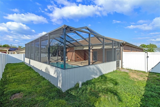 rear view of house featuring glass enclosure, a fenced in pool, a fenced backyard, and a lawn