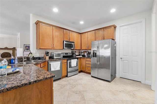 kitchen featuring light tile patterned floors, recessed lighting, brown cabinetry, stainless steel appliances, and a sink