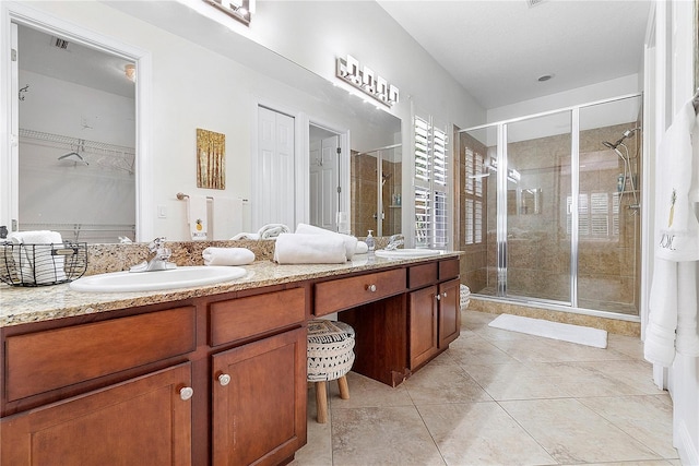 bathroom featuring double vanity, a stall shower, a spacious closet, and a sink