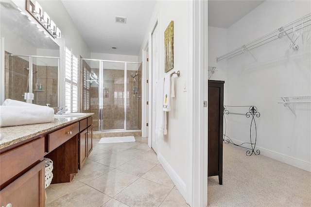 bathroom with visible vents, a spacious closet, a stall shower, and vanity