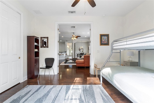 bedroom featuring wood finished floors, visible vents, and arched walkways