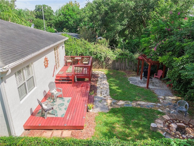 view of yard with a wooden deck, a patio, a fire pit, and fence