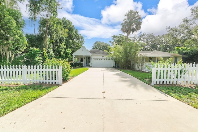 ranch-style home featuring a fenced front yard, an attached garage, and concrete driveway