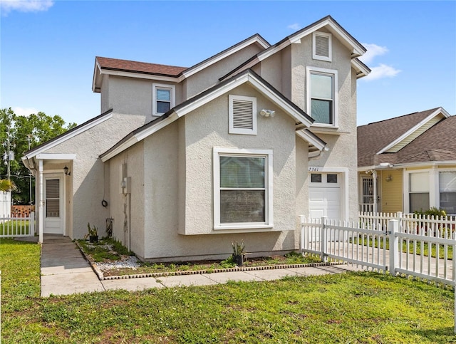 view of front facade with a front yard, fence, and stucco siding