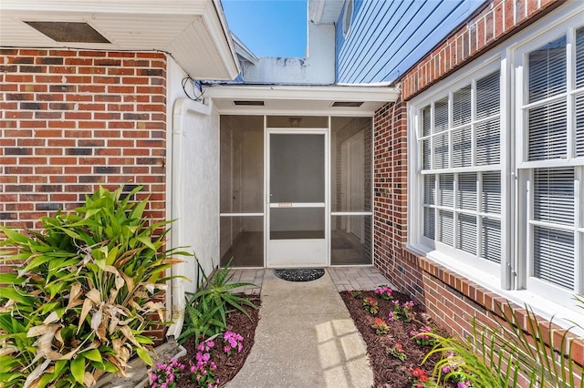 view of exterior entry featuring metal roof and brick siding