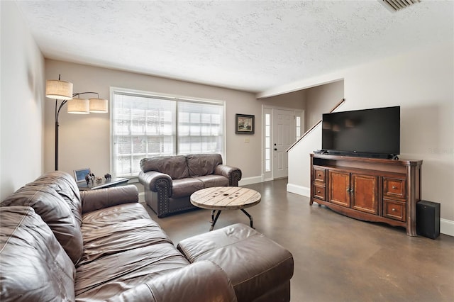 living room featuring visible vents, baseboards, a textured ceiling, and finished concrete flooring